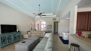 A spacious living room with a sectional sofa, a television, and a ceiling fan. - Beautiful 3-bedroom house in a gated community in Estero. Pool, Spa, Fitness (Fort Myers)