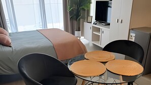 Ett modernt hotellrum med en säng, en TV, en minibar och en sittgrupp med ett bord och stolar.