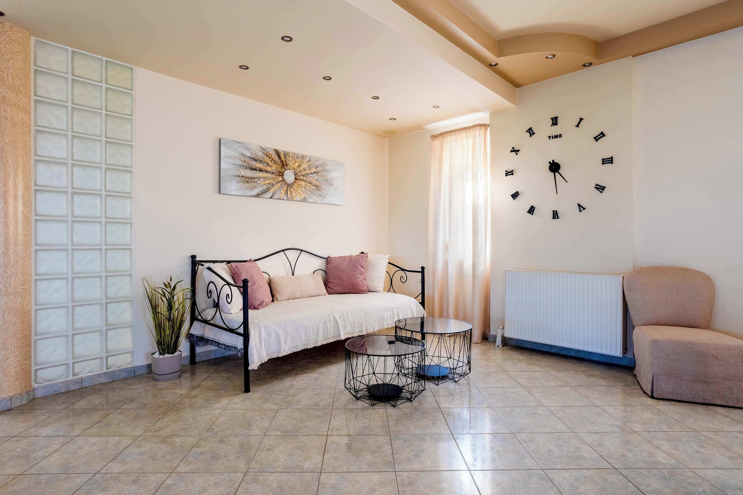 A living room with a sofa, a coffee table, a clock, and a radiator.