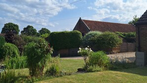 A garden with a brick building, a wooden fence, and a gravel path.