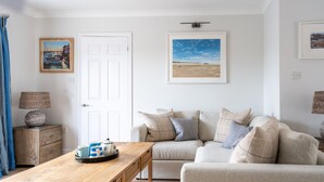 A living room with a wooden coffee table, a beige sofa, and a white door.