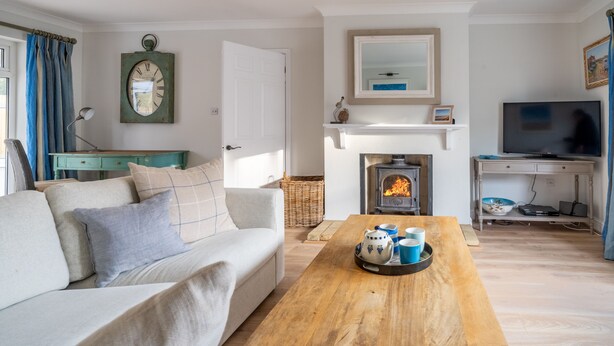 A living room with a sofa, coffee table, fireplace, television, and a clock on the wall.