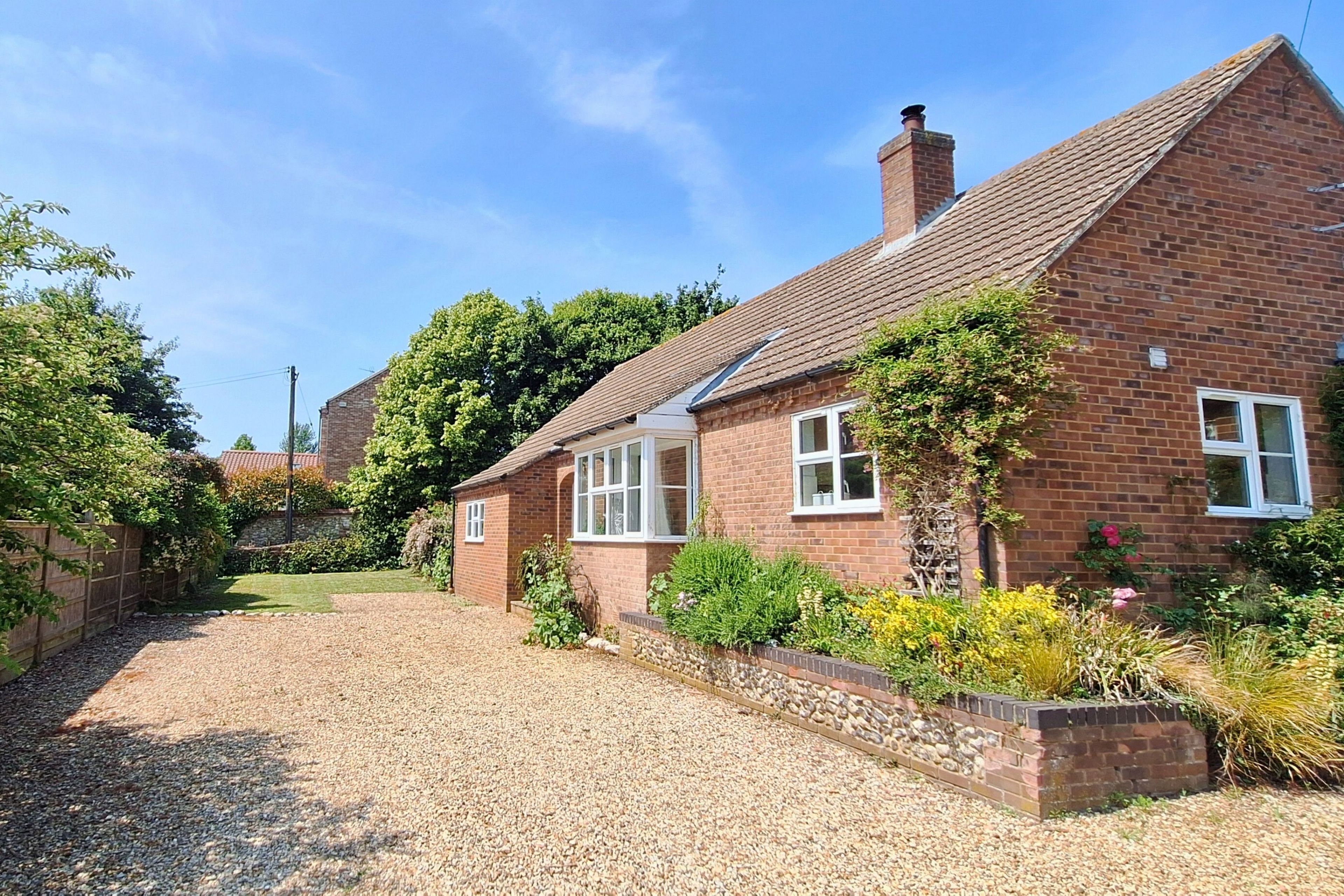 A brick house with a gravel driveway and a garden.