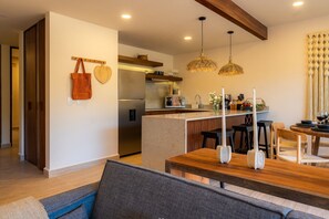 A modern kitchen with a built-in island, pendant lights, and a dining area with a wooden table and chairs.