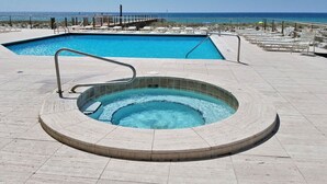 Une piscine avec un jacuzzi et un espace extérieur aménagé avec des chaises longues.