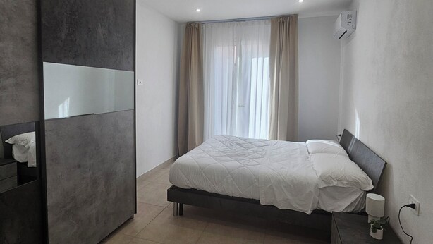 A modern bedroom with a bed, bedside table, and a wardrobe. - Pavifè: vacation home in beautiful Avola, pearl of the Ionian Sea (Avola)