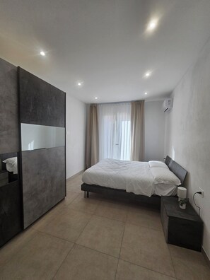 A modern bedroom with a bed, bedside table, and a wardrobe.