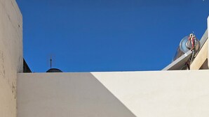 A courtyard with a small window and a door, a concrete floor, and a white wall. - Pavifè: vacation home in beautiful Avola, pearl of the Ionian Sea (Avola)