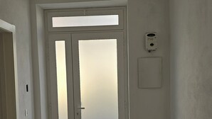 A room with a large door, a light switch, and a thermostat on the wall. - Pavifè: vacation home in beautiful Avola, pearl of the Ionian Sea (Avola)