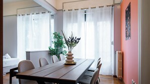 Un comedor con una mesa de madera, sillas y un jarrón con flores.