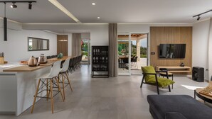 A modern kitchen with a central island, dining area with chairs, a TV, and a seating area with a sofa and chairs. - Villa Lumi Zadar Villas (Murvica)