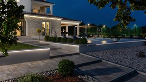 A modern house with a stone facade, outdoor seating, and a well-lit patio area. - Villa Lumi Zadar Villas (Murvica)