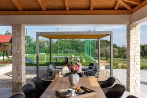Relax in a serene outdoor space with a view of the soccer field, featuring a table, vase, and refreshments.