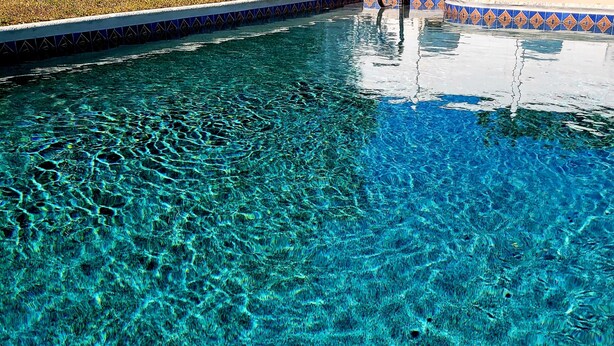 A clear pool with visible ripples on the water surface. - Charming 2-bedroom house in beautiful Port Charlotte with Pool, Hot tub, & WiFi (Port Charlotte)
