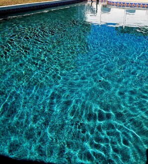 Une piscine aux eaux claires, dont la surface est légèrement agitée et présente de petites ondulations.