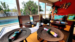 A room with a glass table, wicker chairs, and a view of a swimming pool. - Charming 2-bedroom house in beautiful Port Charlotte with Pool, Hot tub, & WiFi (Port Charlotte)