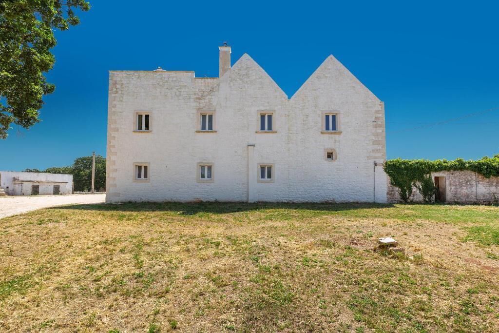 Un edificio blanco con fachada simétrica, varias ventanas y techo plano.