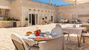 An outdoor dining area with stone walls, tables, and chairs.