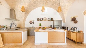 A kitchen with a central island, stone arch ceiling, hanging pendant lights, and wooden cabinetry.