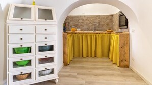 A kitchen with an archway, a white cabinet with multiple drawers, and yellow checkered curtains. - The Villa Resort, sleeps 8 + shared pool (MARTINA FRANCA)