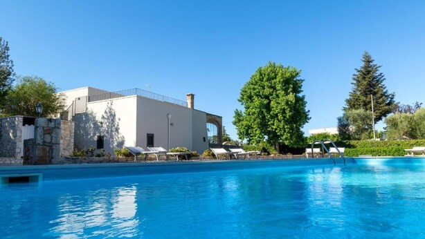 A swimming pool with lounge chairs and a building with a white facade and stone accents. - The Villa Resort, sleeps 8 + shared pool (MARTINA FRANCA)
