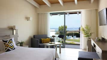 Habitación de hotel moderna con una cama grande, un sofá, una mesita y un balcón con vistas al mar.
