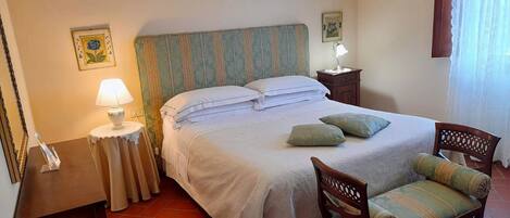 A neatly arranged bedroom with a bed, bedside tables, a chair, and a lamp.