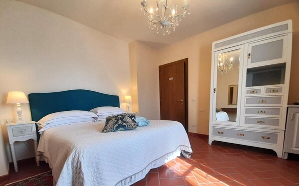 Ein Schlafzimmer mit Bett, Nachttischen, einem Schminktisch und einer Chandelier.