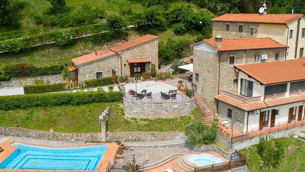 Una villa de piedra con piscina, zona de estar al aire libre y exuberante vegetación.