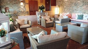 Un rincón acogedor con muebles de mimbre, una pared de piedra y una puerta de madera.