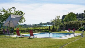 Una piscina con sedie rosse e un pergolato.