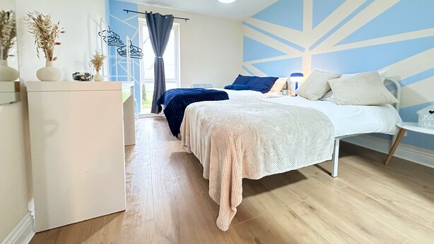 Un dormitorio moderno con una cama grande, un aparador y vistas al exterior.