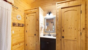 Un baño de cabaña de madera con dos puertas, un lavabo y un espejo.