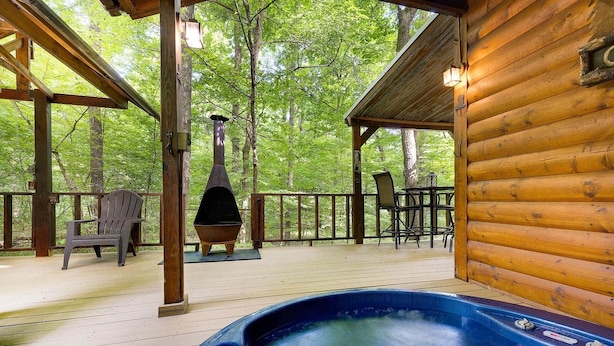 Una cabaña de madera con jacuzzi, zona de estar exterior y estufa de leña.