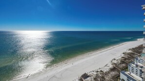 Un hotel frente a la playa con arena, vista al océano y cielo despejado.