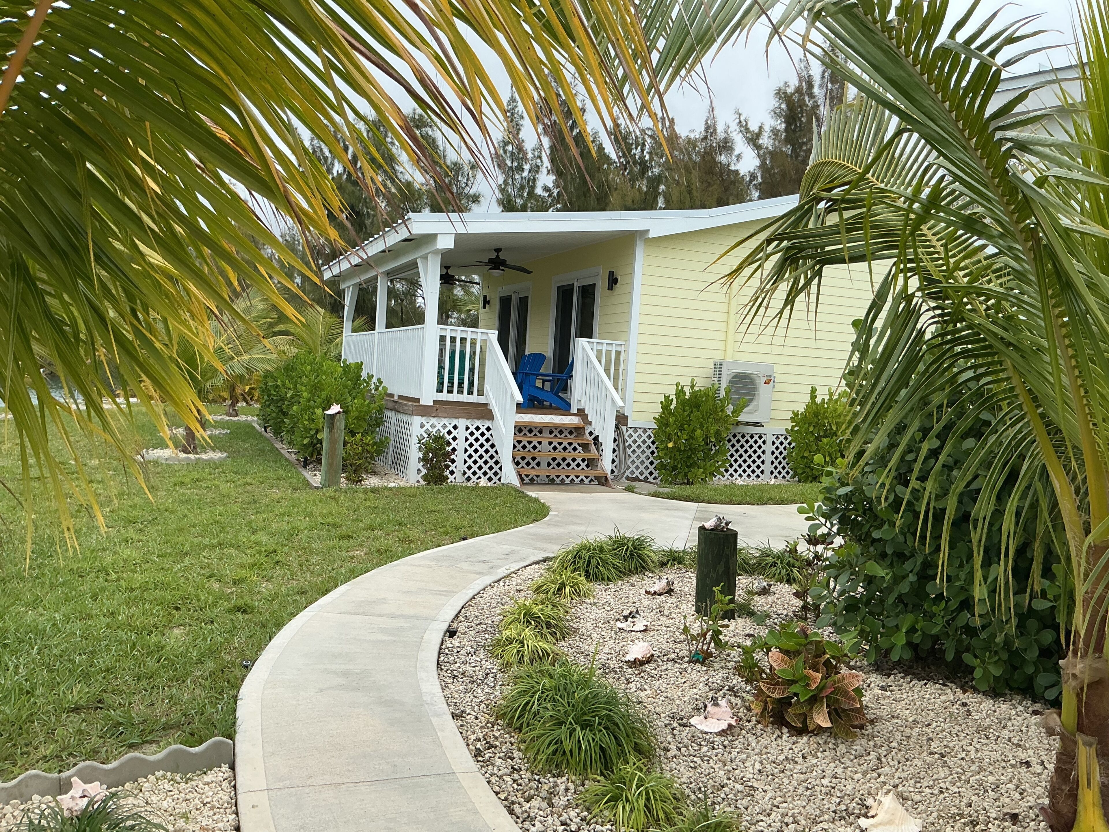 A house with a porch, a covered deck, and a pathway leading to the entrance.
