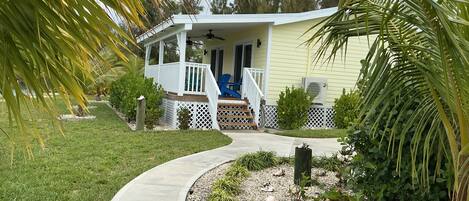 A house with a porch, a covered deck, and a pathway leading to the entrance.