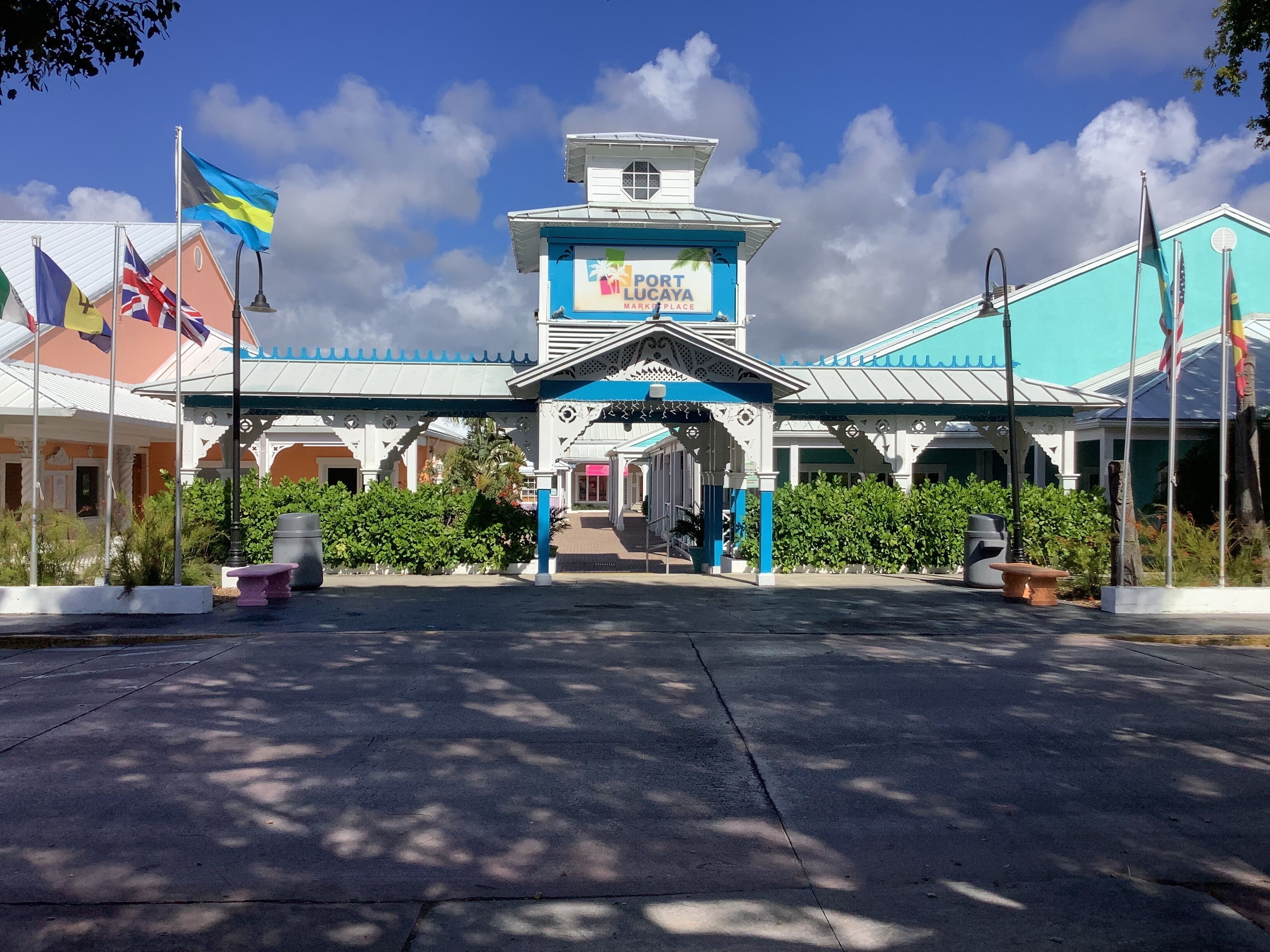 Mercado Port Lucaya con una entrada central, rodeado de banderas y follaje.