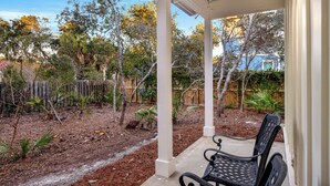 A covered patio with a bench, surrounded by a garden with various plants and trees. - Seagrove Beach - Private Pool - Pet Friendly (Santa Rosa Beach)