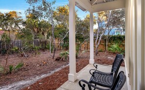 A covered patio with a bench, surrounded by a garden with various plants and trees. - Seagrove Beach - Private Pool - Pet Friendly (Santa Rosa Beach)