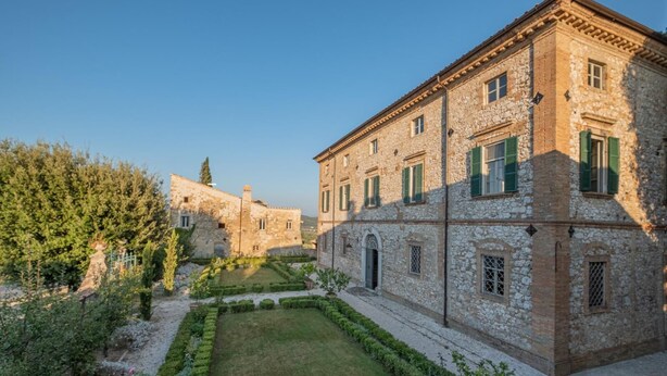 A stone building with a courtyard, featuring a well-maintained lawn and a variety of shrubs. - Historic villa with swimming pool surrounded by nature (Umbria)