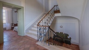 A grand staircase with a wooden handrail and wrought iron balusters, leading to a landing with a decorative wall. - Historic villa with swimming pool surrounded by nature (Umbria)