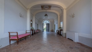 A hallway with arched ceilings, a bench, and a door leading to a garden. - Historic villa with swimming pool surrounded by nature (Umbria)