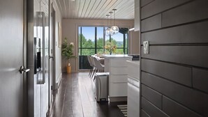 A modern kitchen with a large window, a dining area, and a potted plant.