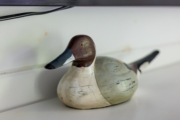Una figurita de pato de madera sobre una superficie blanca.