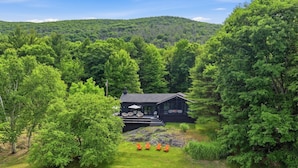 A cabin surrounded by dense forest, with a deck and outdoor seating area.