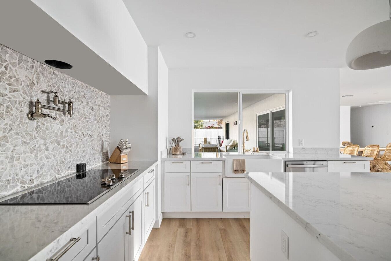 Une cuisine moderne avec des meubles blancs, un plan de travail en marbre et un pare-feu orné d’un motif de pierre.