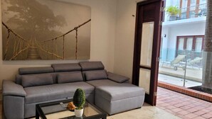 Una sala de estar moderna con un sofá seccional gris, una mesa de centro de vidrio y un cuadro abstracto grande en la pared.
