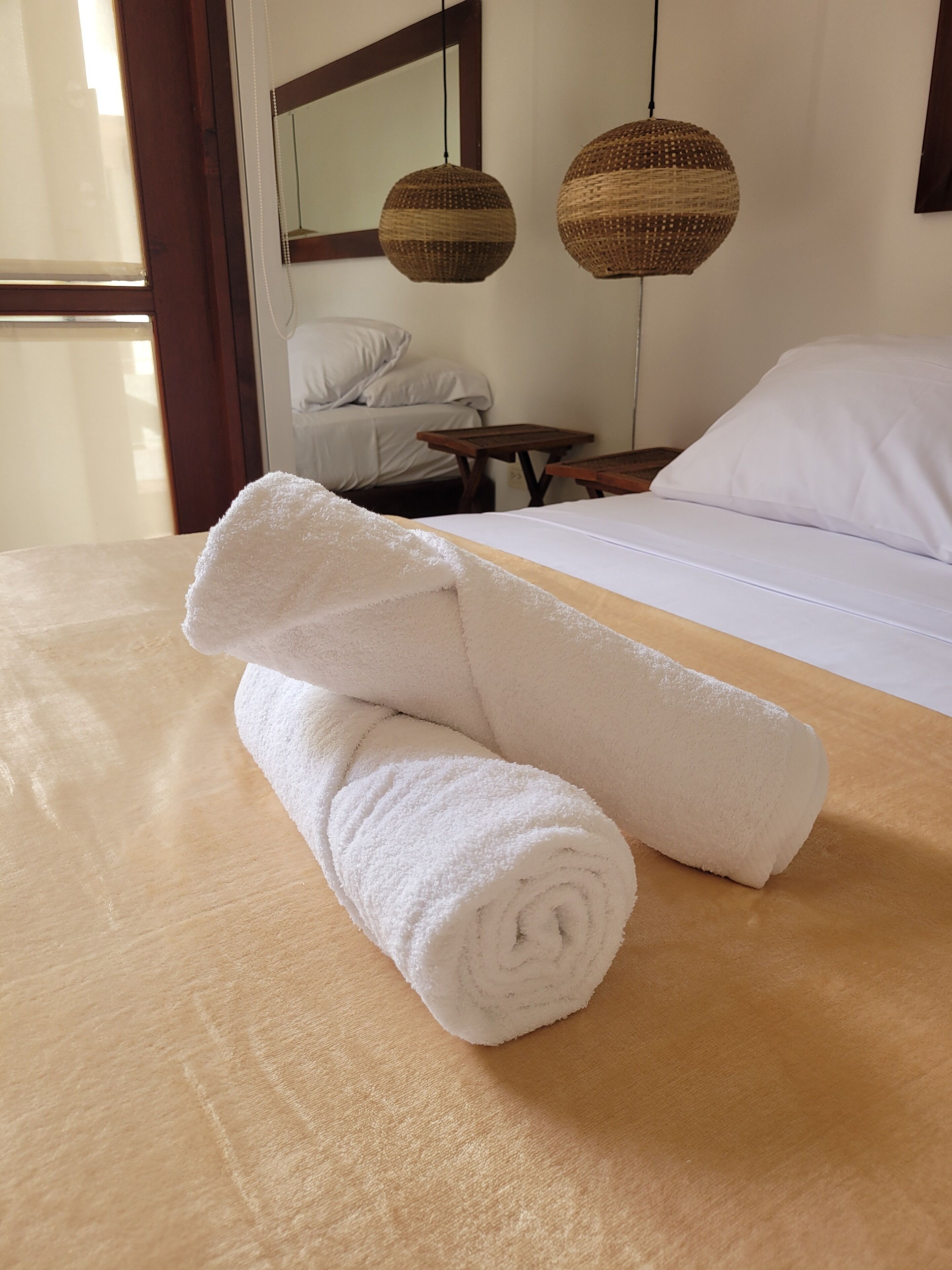 A neatly made bed with white linens and a rolled white towel on the bed.