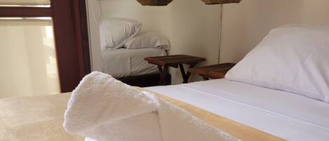 A neatly made bed with white linens and a rolled white towel on the bed.